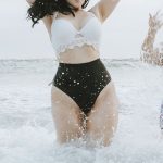 dos mujeres curvy se bañan en el mar y salpican con el agua